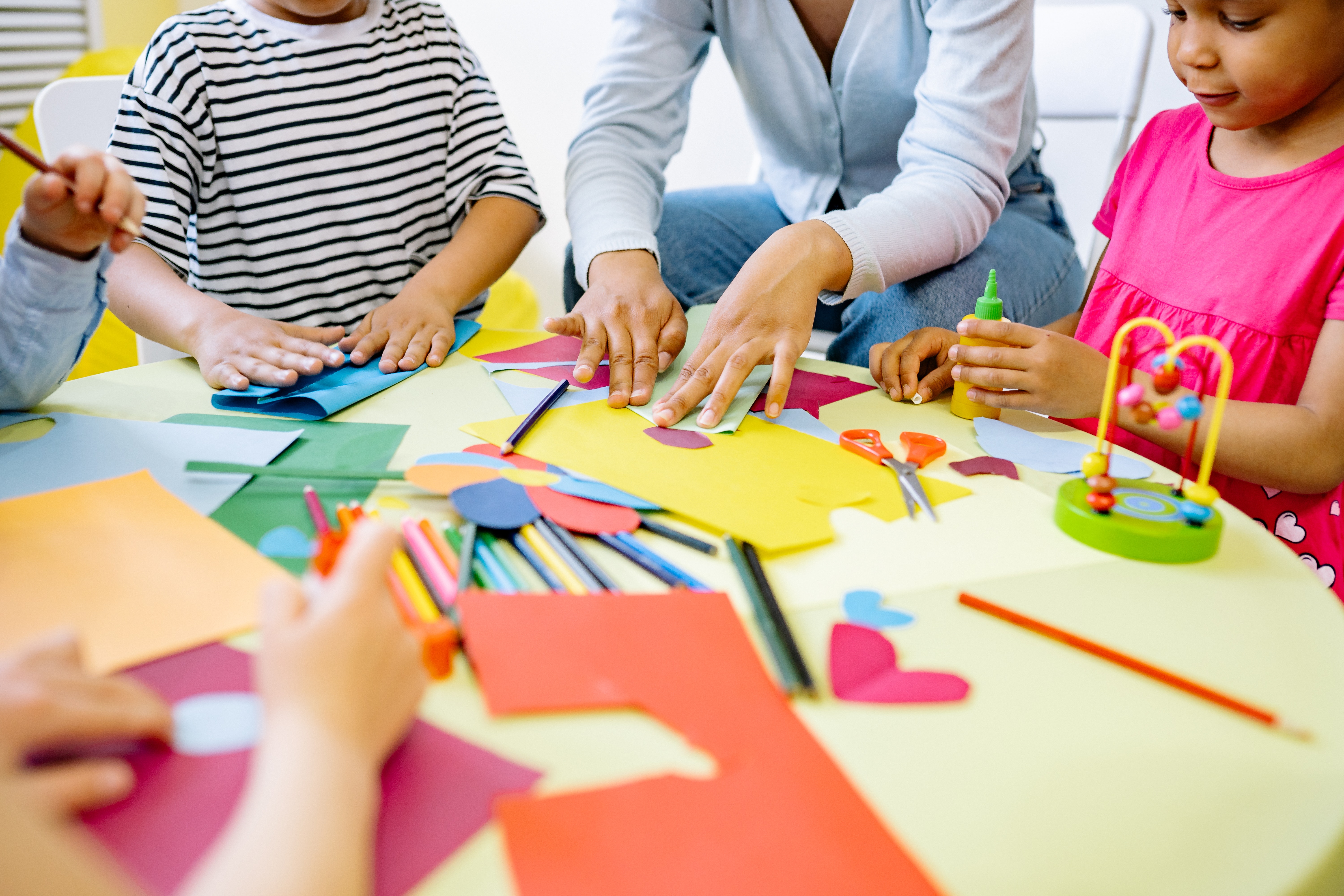 teacher and students at table working with materials