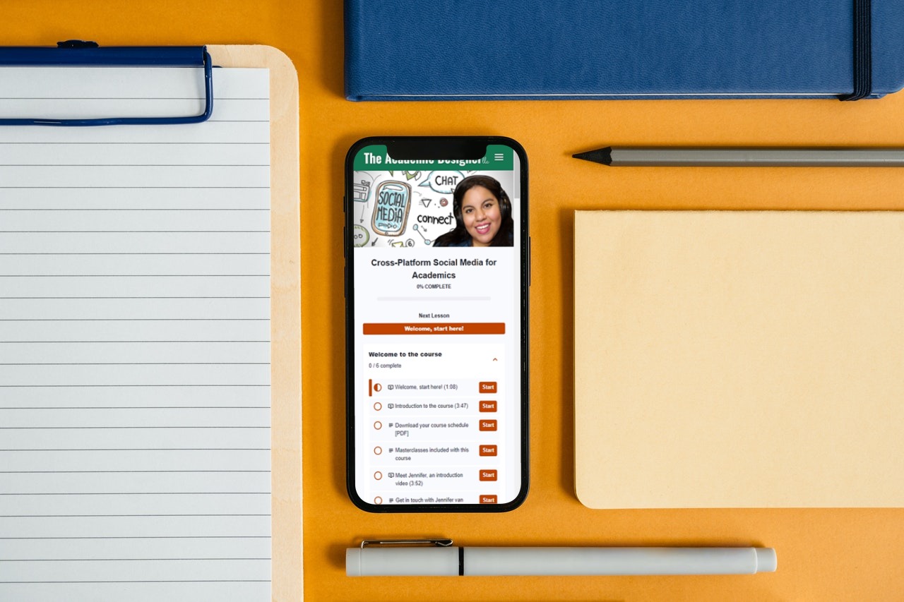 Flatlay desk with notebooks, pen, and mobile phone. On the phone is a screenshot of the course curriculum.