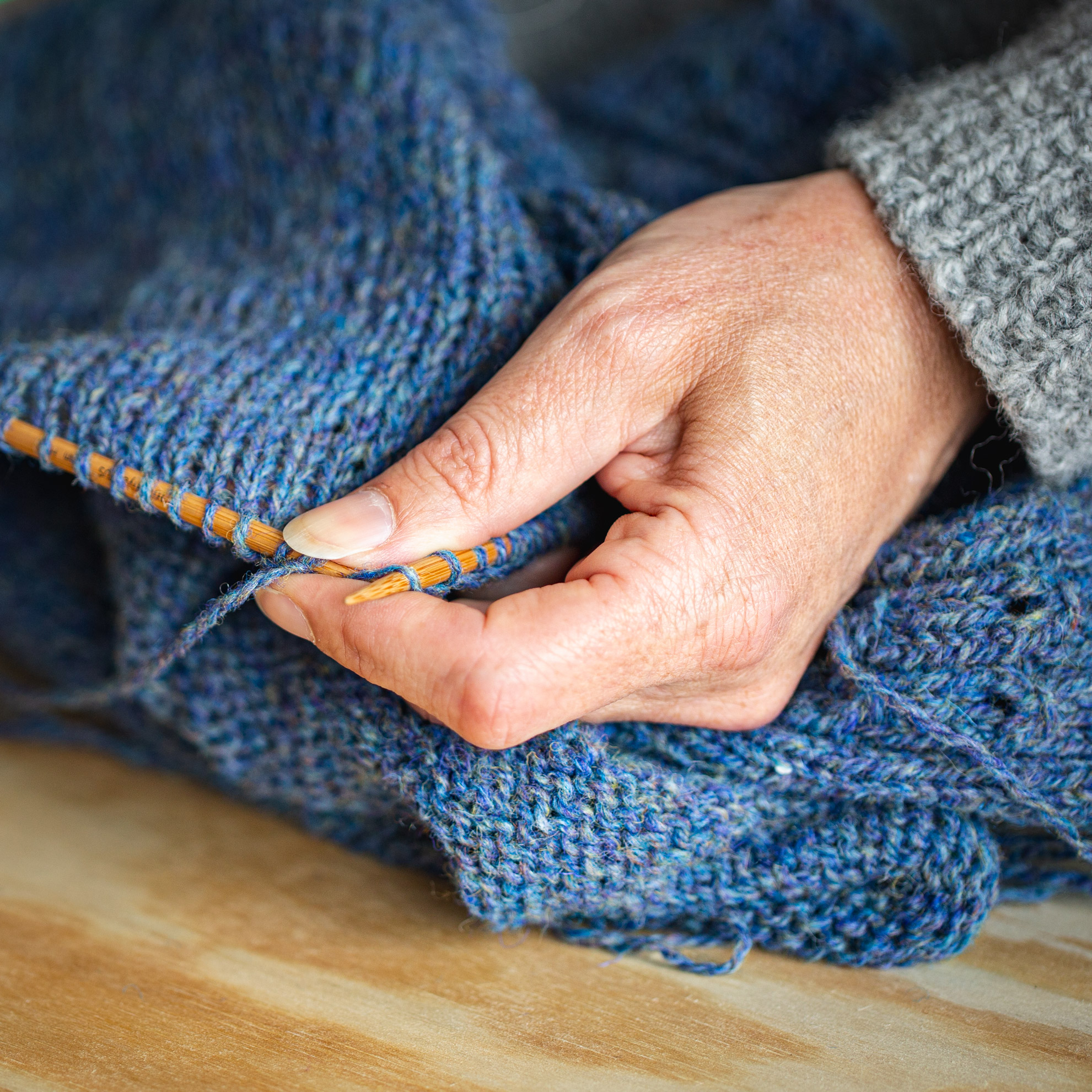 Knitting needles with blue garment on them.