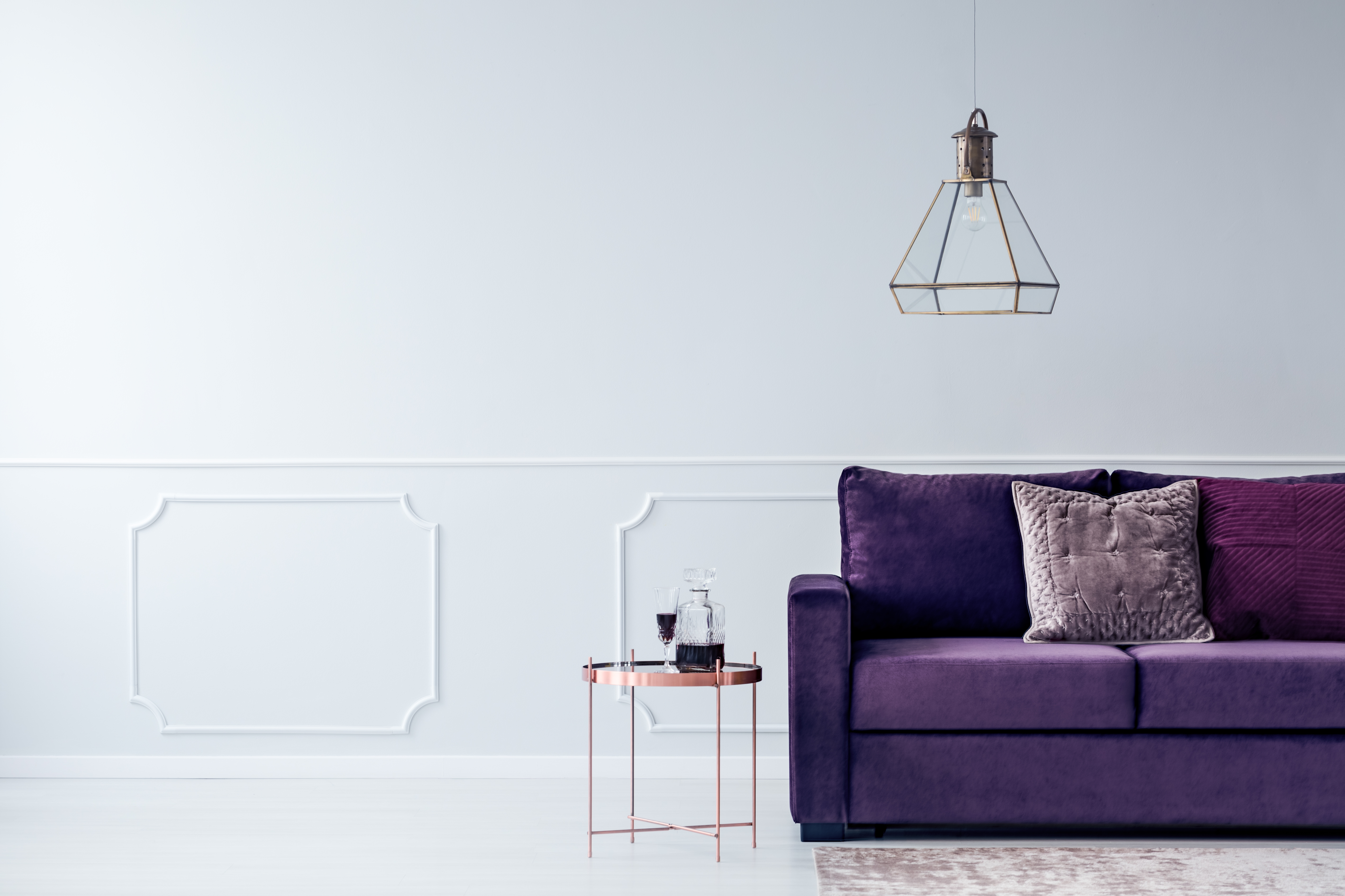 Purple couch with rose gold table next to it with wine on table.