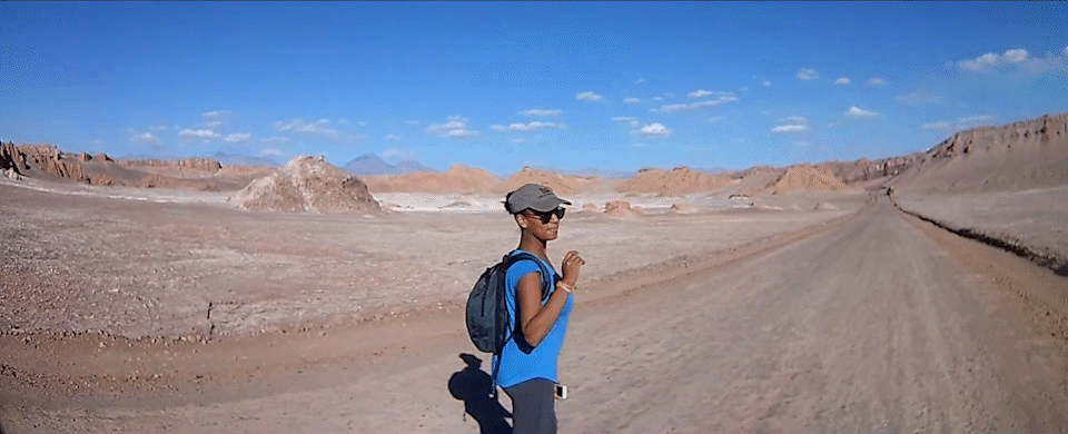 Instructor Olivia Hiking in the Atacama Desert, turning around and giving a thumbs up while smiling