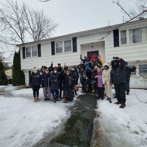 26 memners of a family standing outside in front of a house they saved