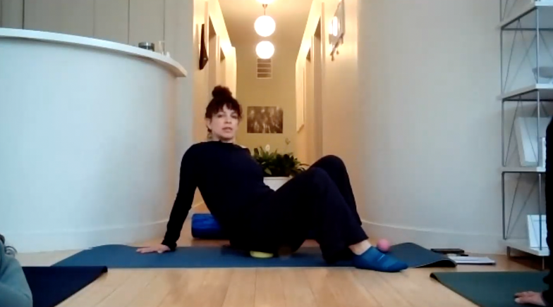 Instructor sitting her right hip on a therapy ball.