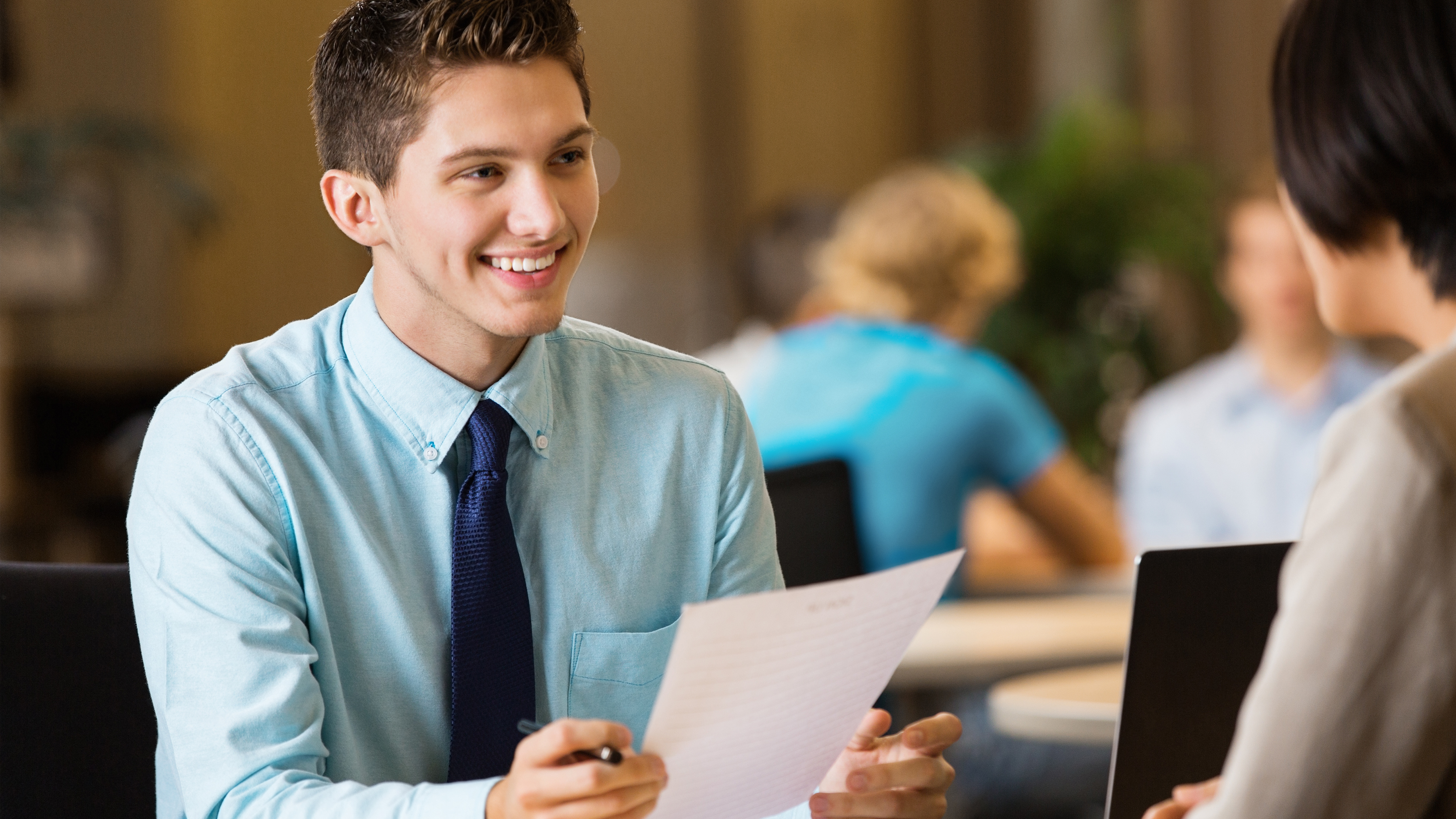 student holding paper in an interview with someone