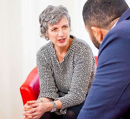 Tosca discusses civil society issues with client, seated in red chair