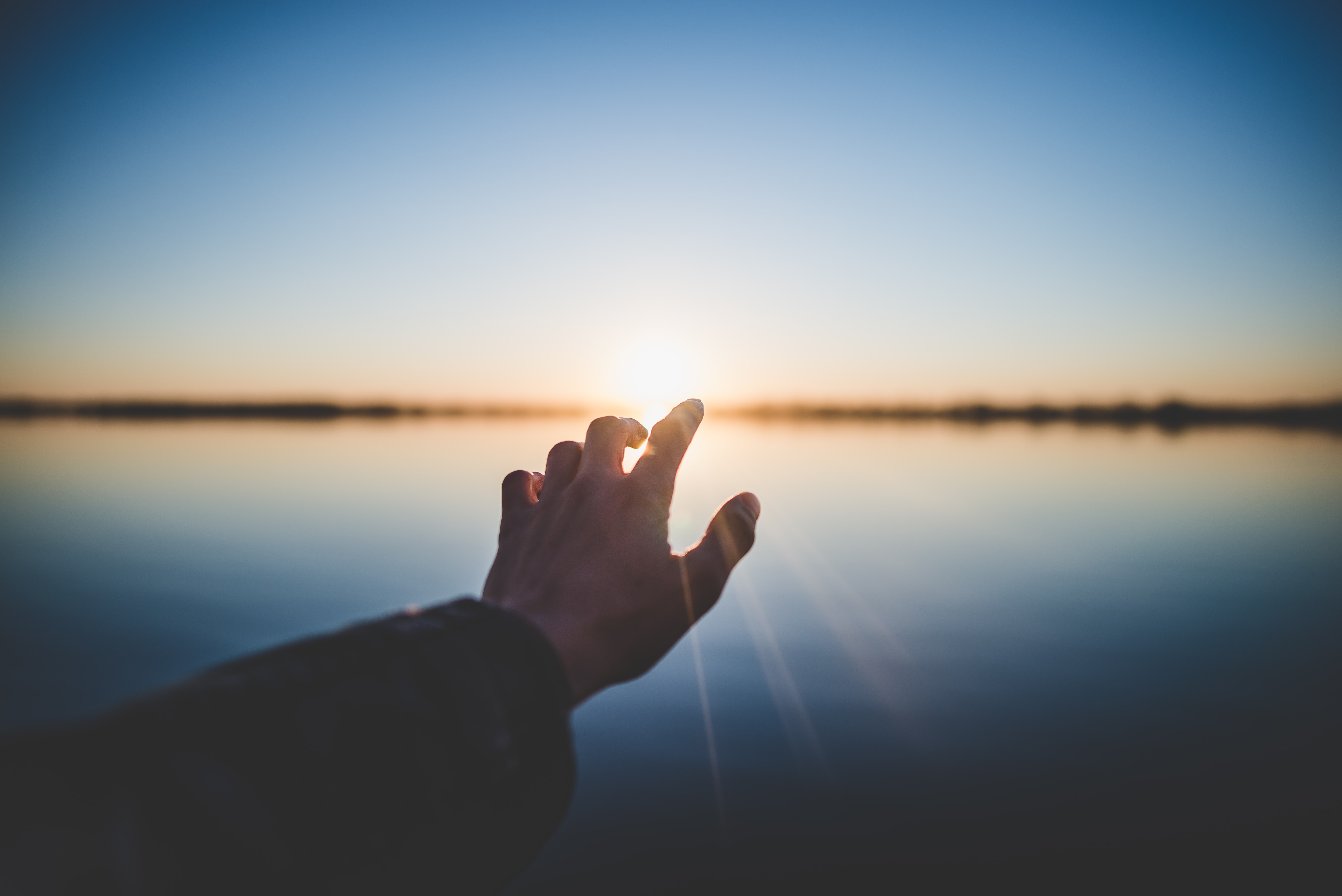 a finger reaching towards sunrise