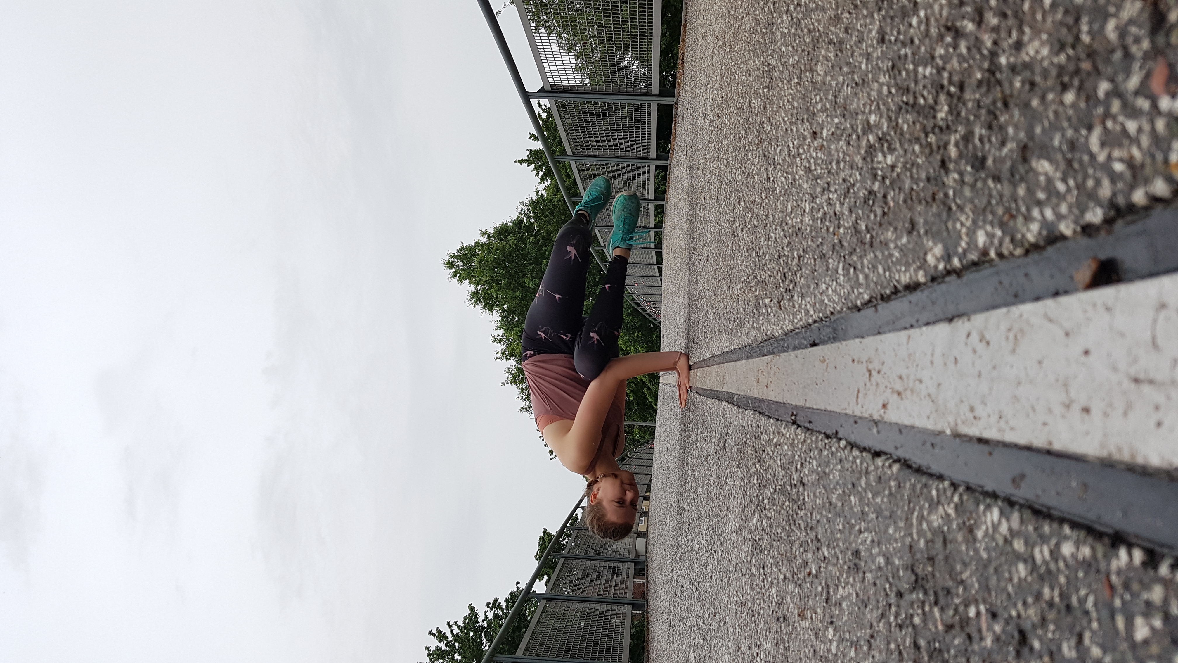 Ein Trennstreifen zwischen Rad- und Fußweg auf einer Brücke. Frederike macht Parsva Bakasana, die seitliche Krähe in der Mitte.