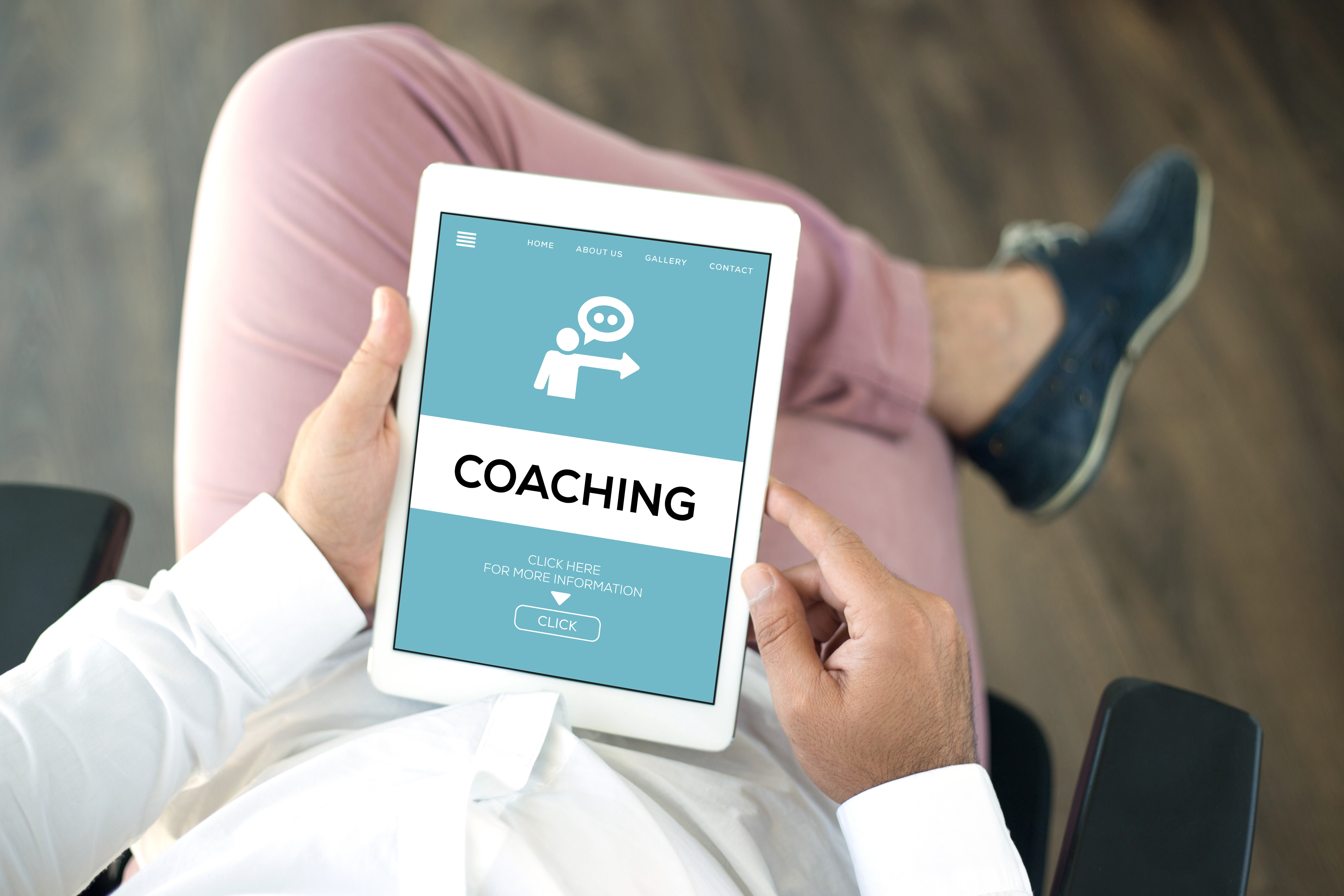 a person seated and holding an ipad that says coaching