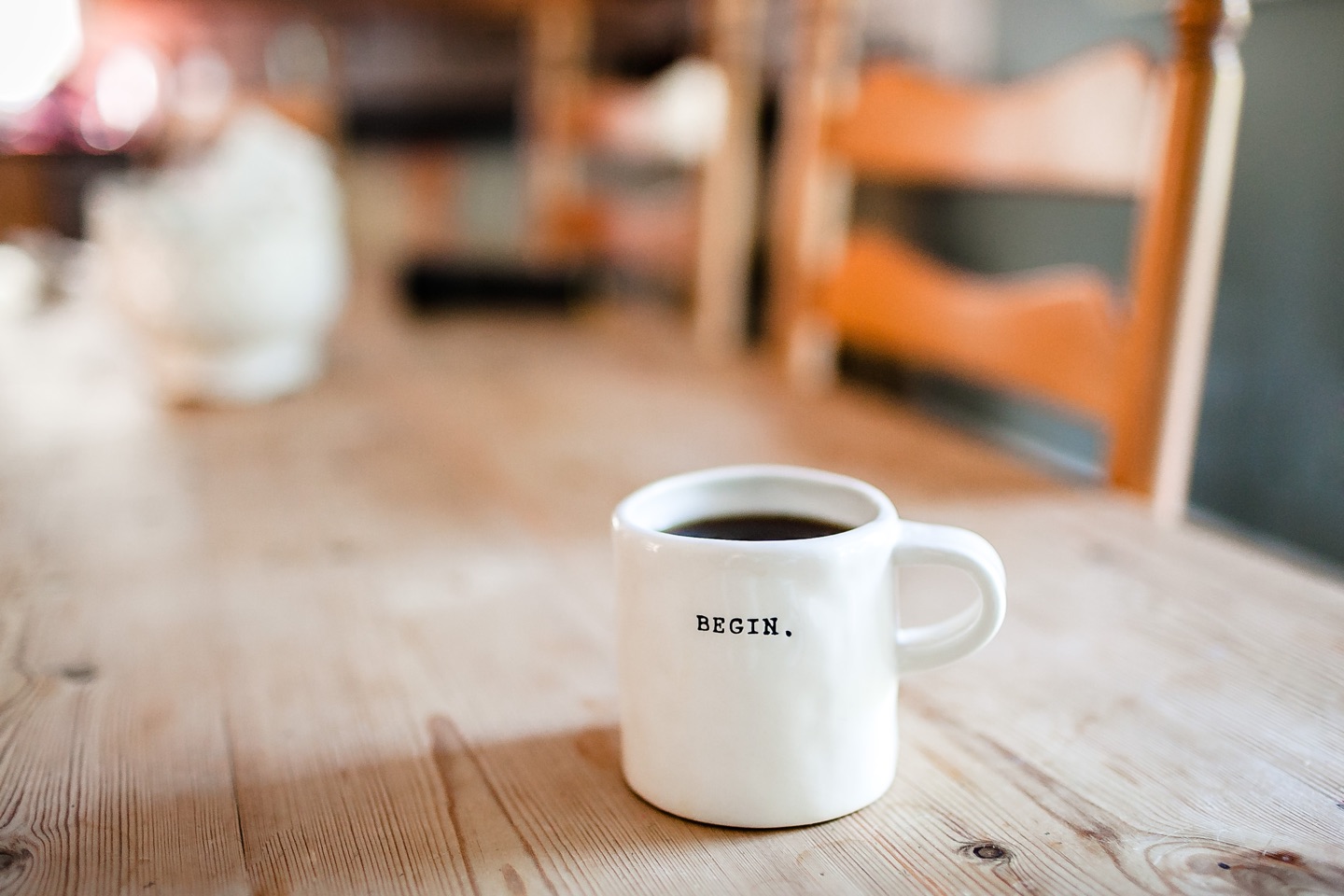 Coffee mug that says "begin" on a kitchen table