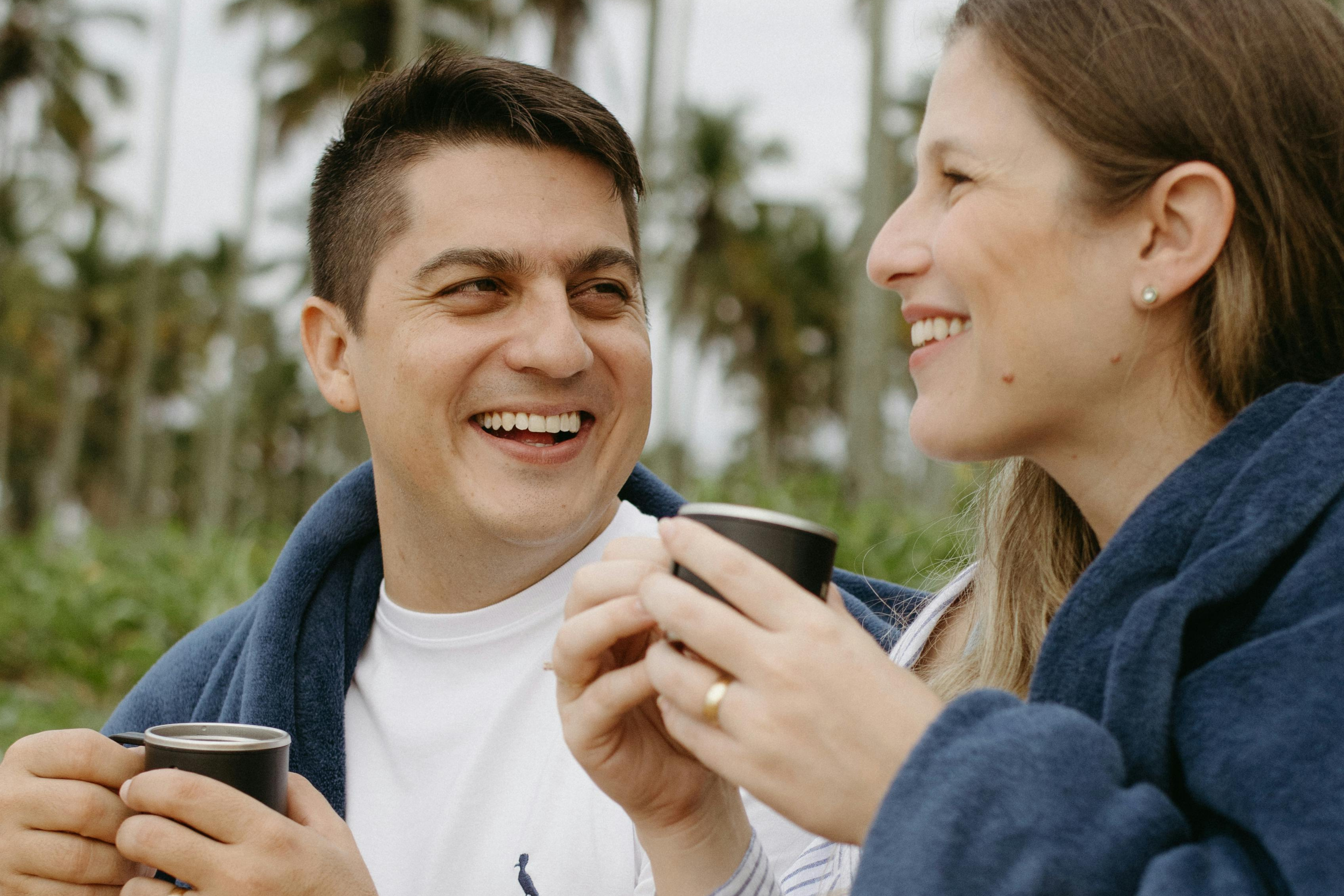 man in white shirt having coffee outside with woman in blue sweater