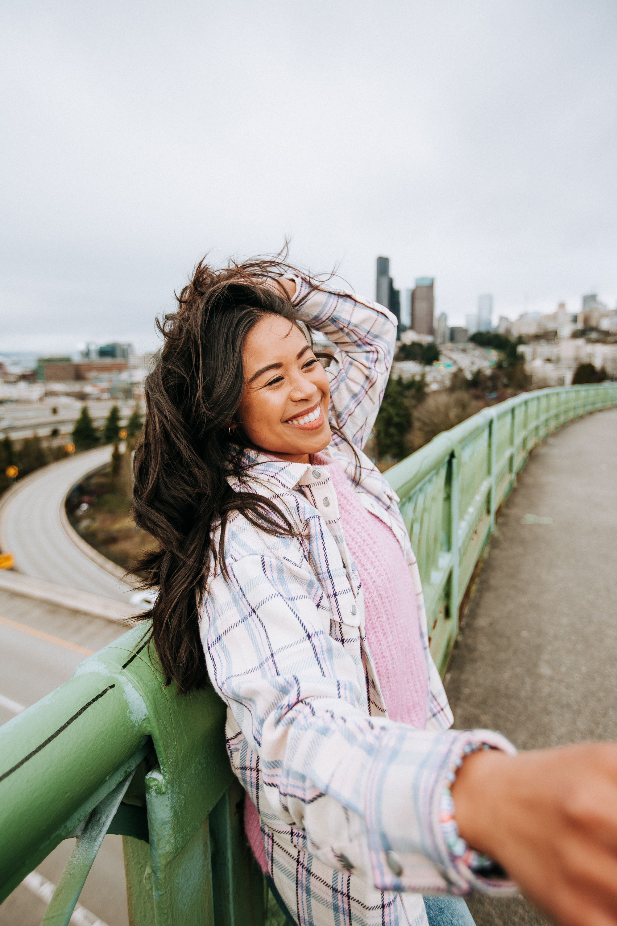 Leaning against the green railing, smiling at the camera