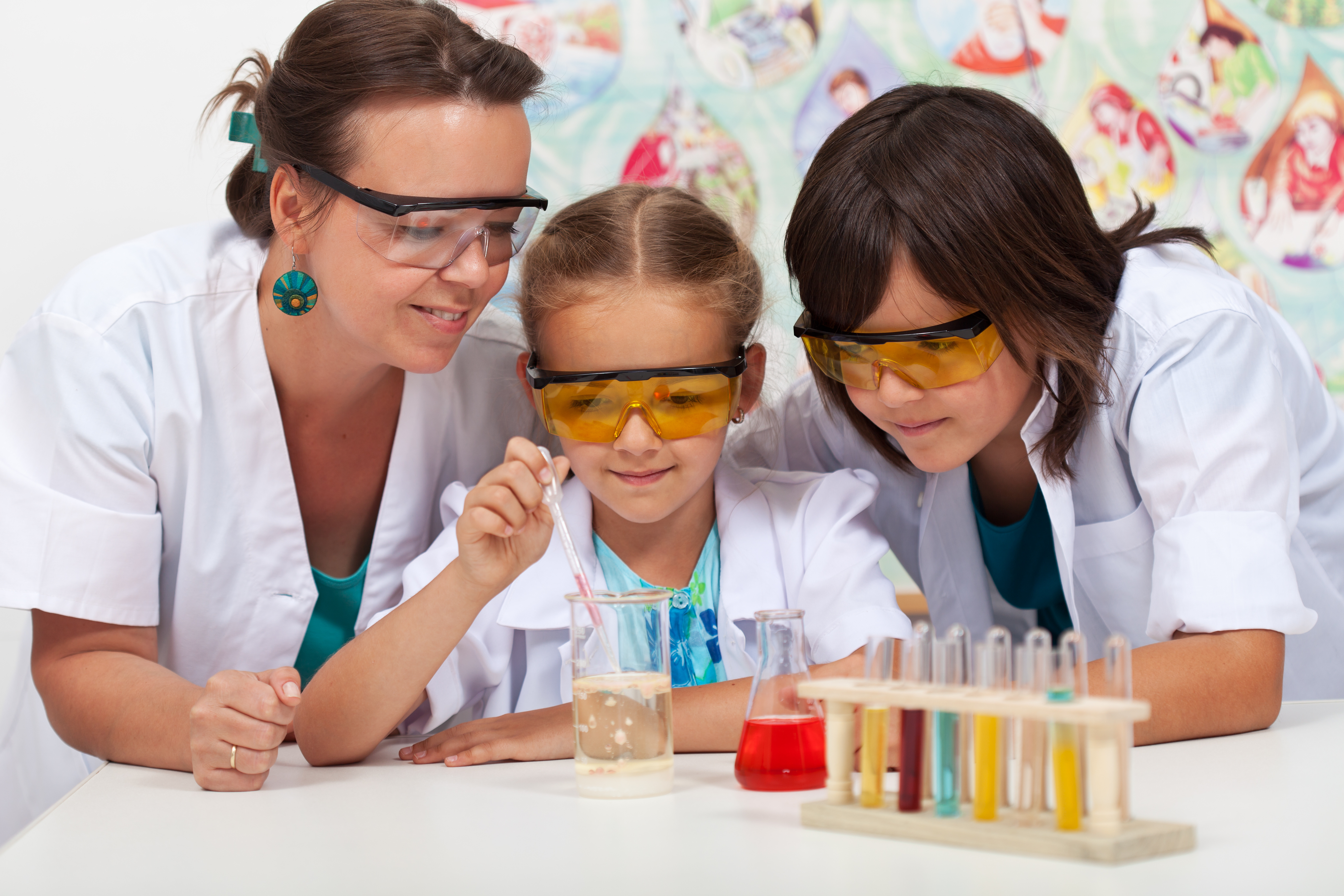 A teacher and 2 students performing a chemistry experiment