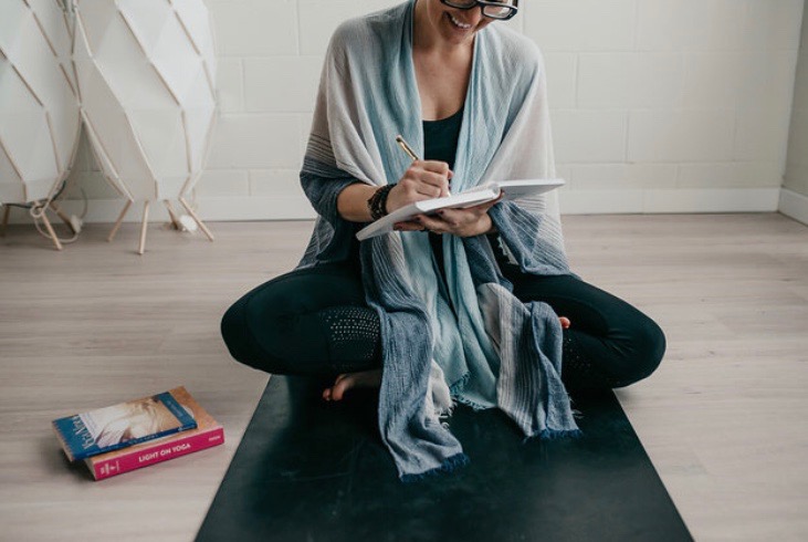 Melissa is sitting on the floor writing in a journal