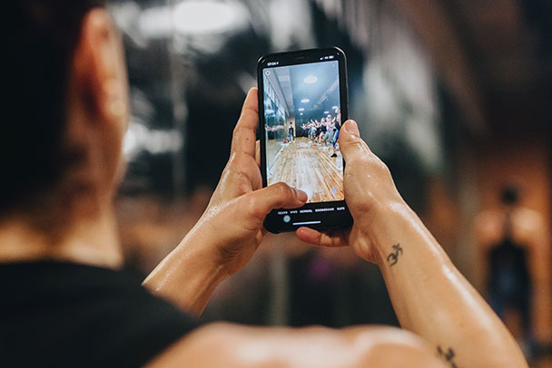 Mujer agarra su smatphone y graba una clase de entrenamiento en vivo