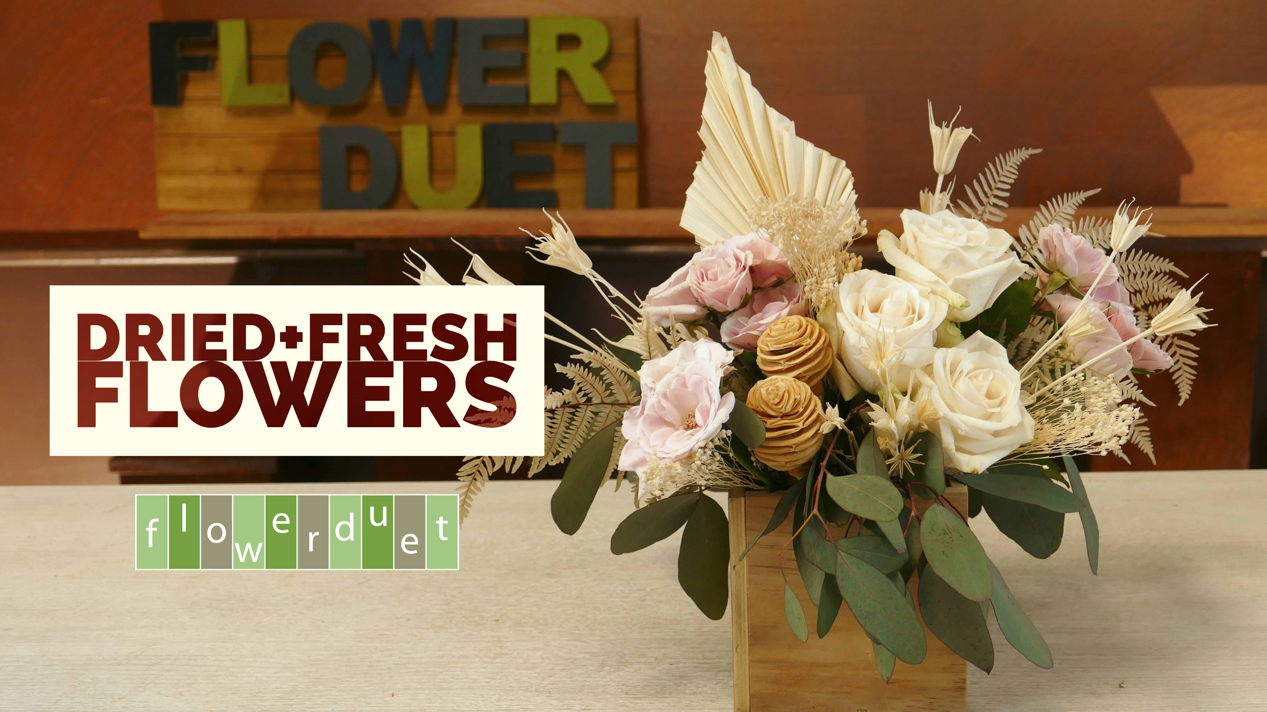 Dried flowers with pink fresh flowers in a wooden container