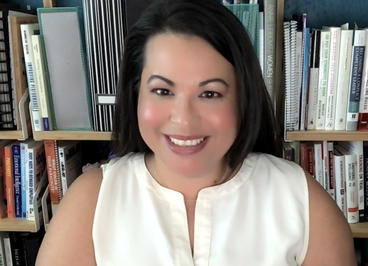 Grisel Scarantino smiling at you with a bookshelf of resources and books in the background