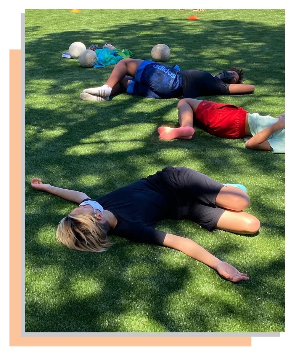 Students lying on grass in a spinal twist