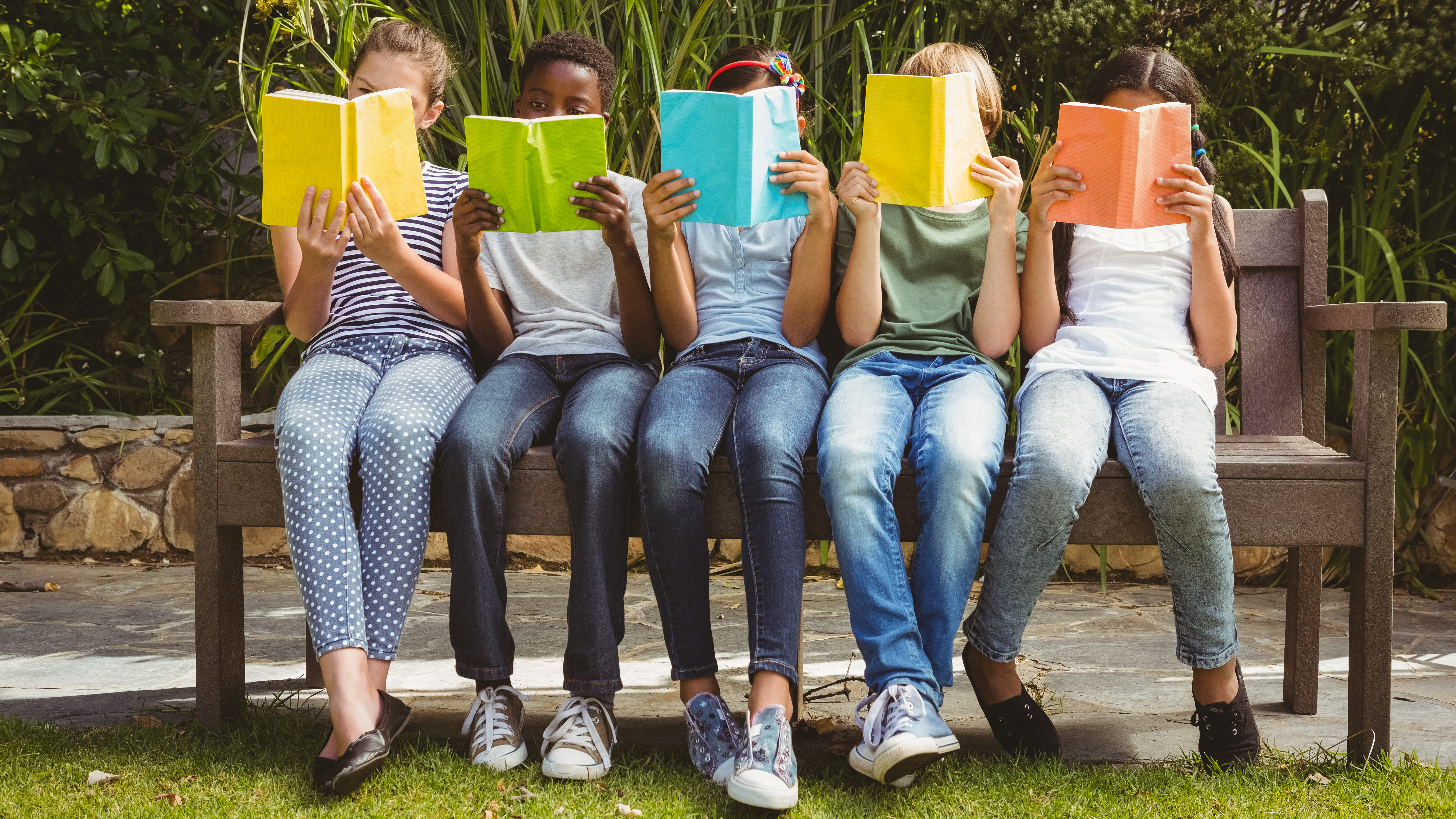 students reading books on a bench