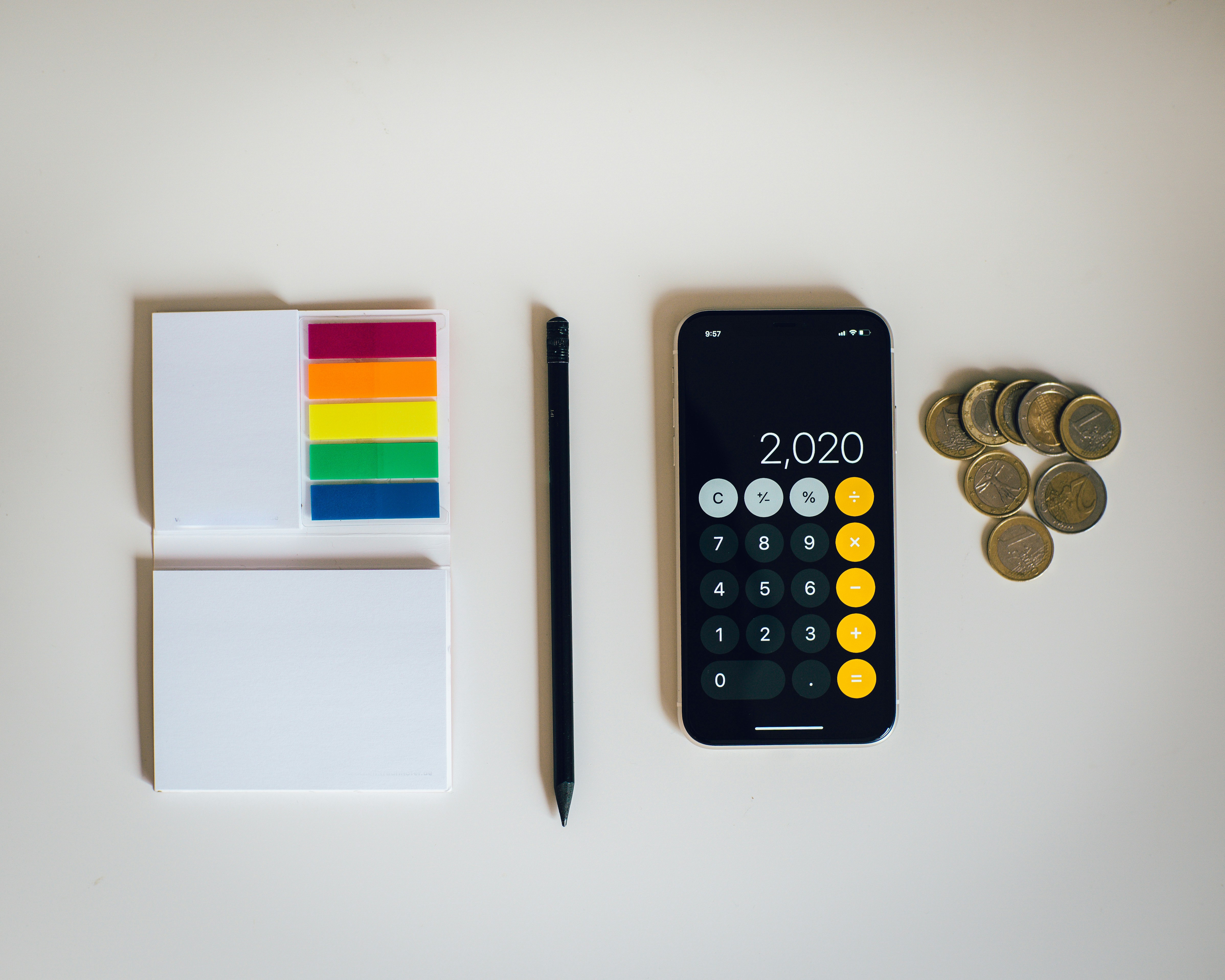 page flags, a pen, a calculator, and some coins on a table