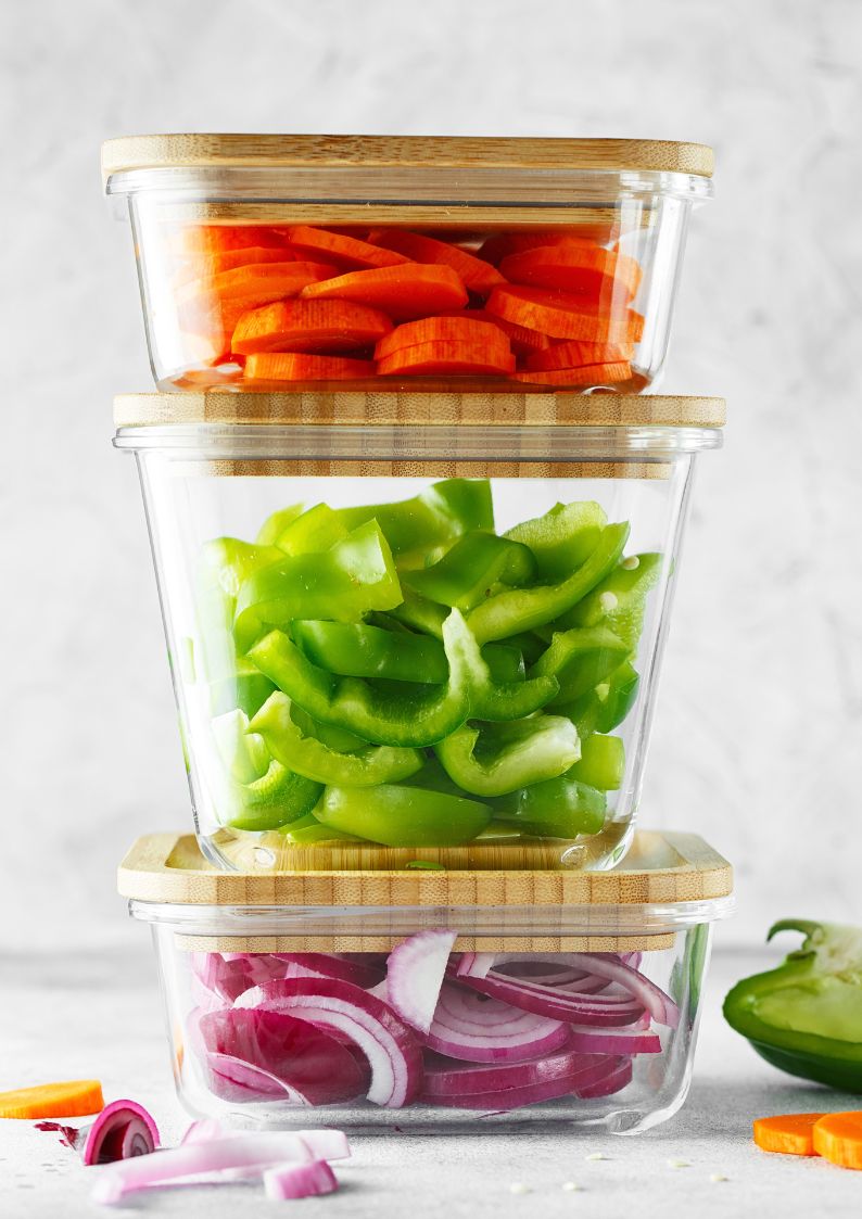 containers ofr onions, peppers, and carrots stacked on top of each other. 