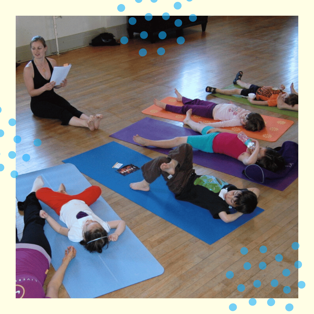 a family yoga class during relaxation time where families are realxed on their mats with arms around each other for comfort.