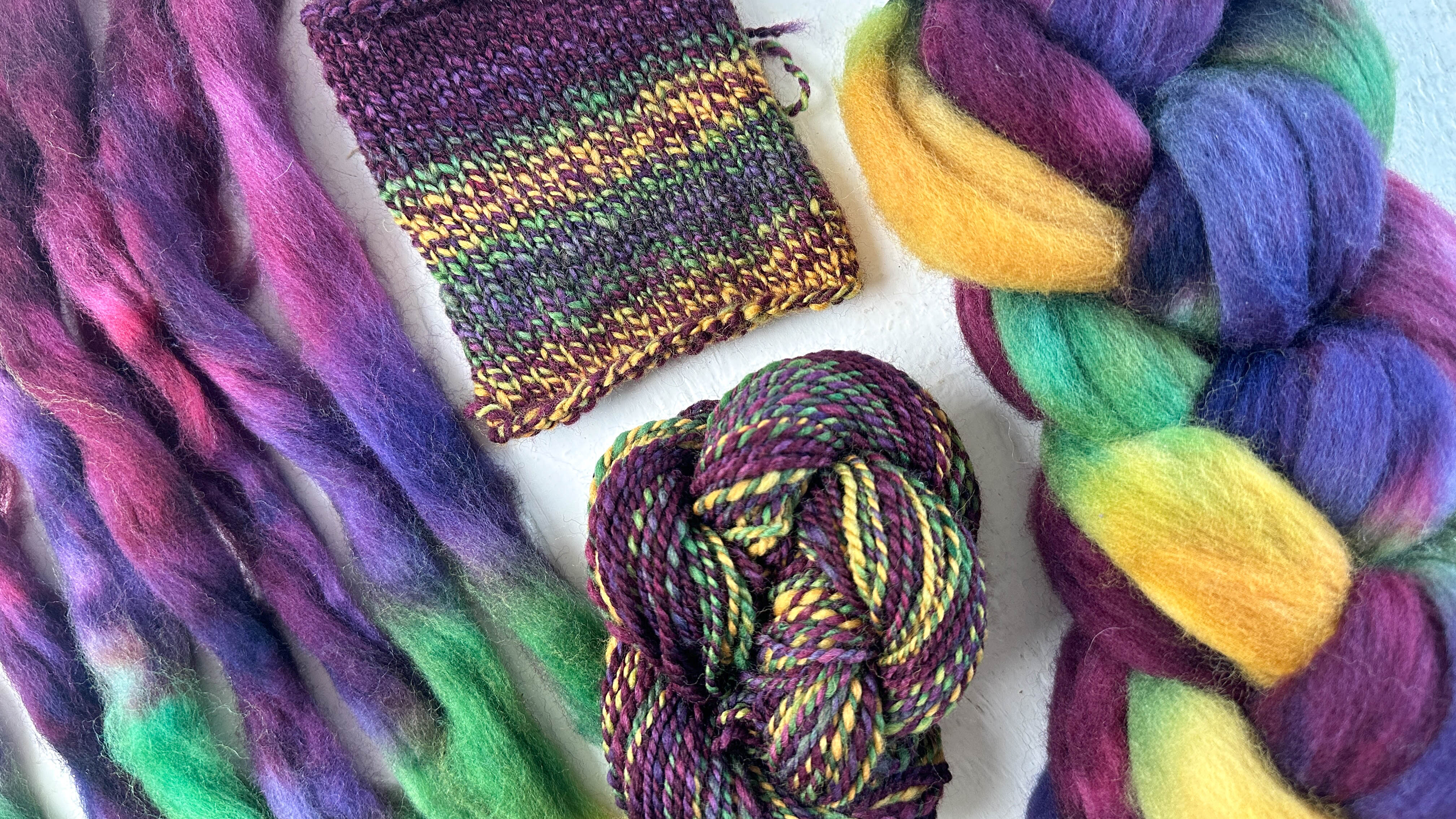 A selection of wool roving, handspun yarn twist, and a knitted swatch highlighting color variations, the roving is in purple, pinks, greens, and yellow