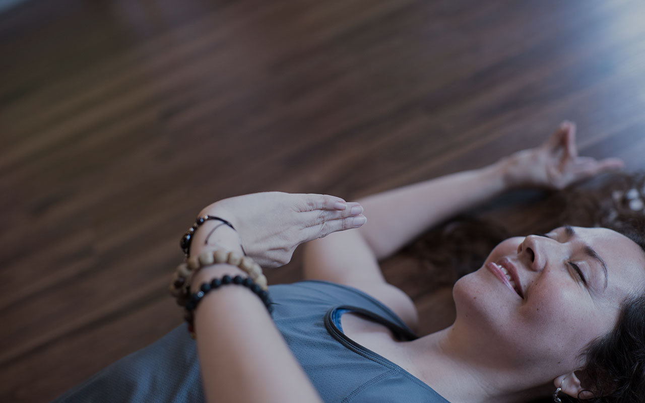 Mujer sonriente en el suelo practica yoga con un rostro de calma y paz