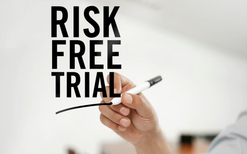 image shows hand with pen writing &quot;risk free trial&quot;