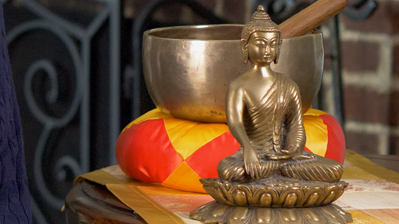 A golden Buddha statue beside a meditation bowl