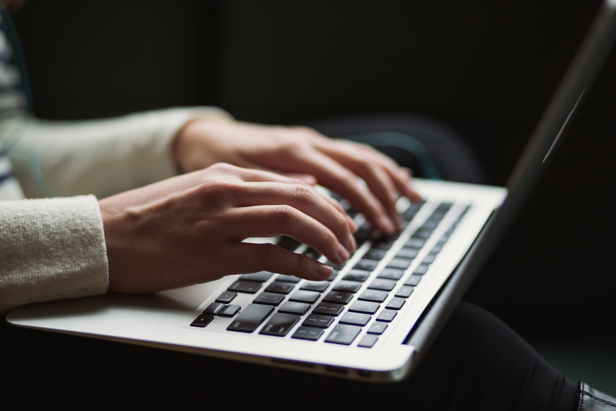 Hands typing essay on laptop