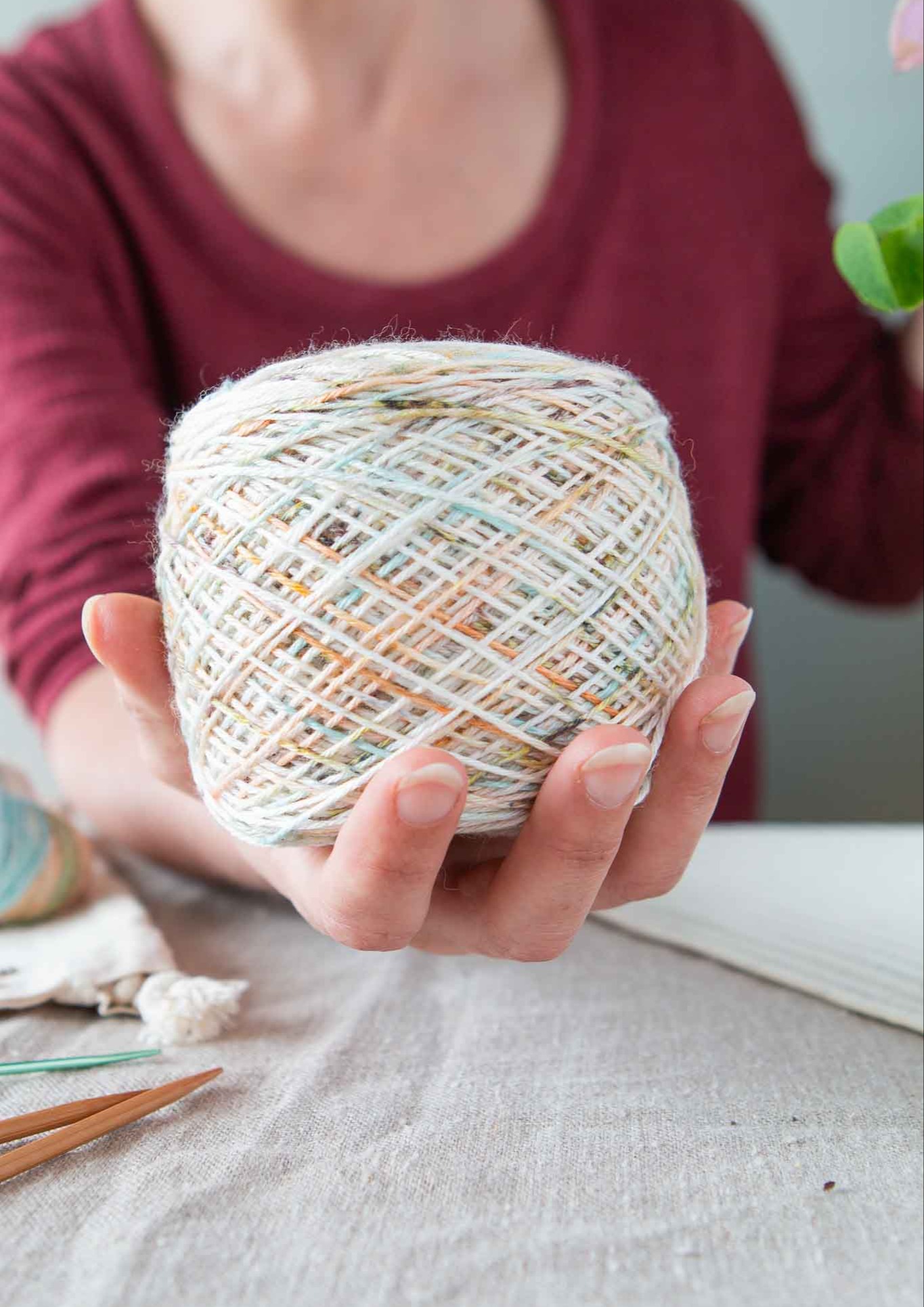 Hand holding a ball of wound hand-dyed yarn to the camera. 