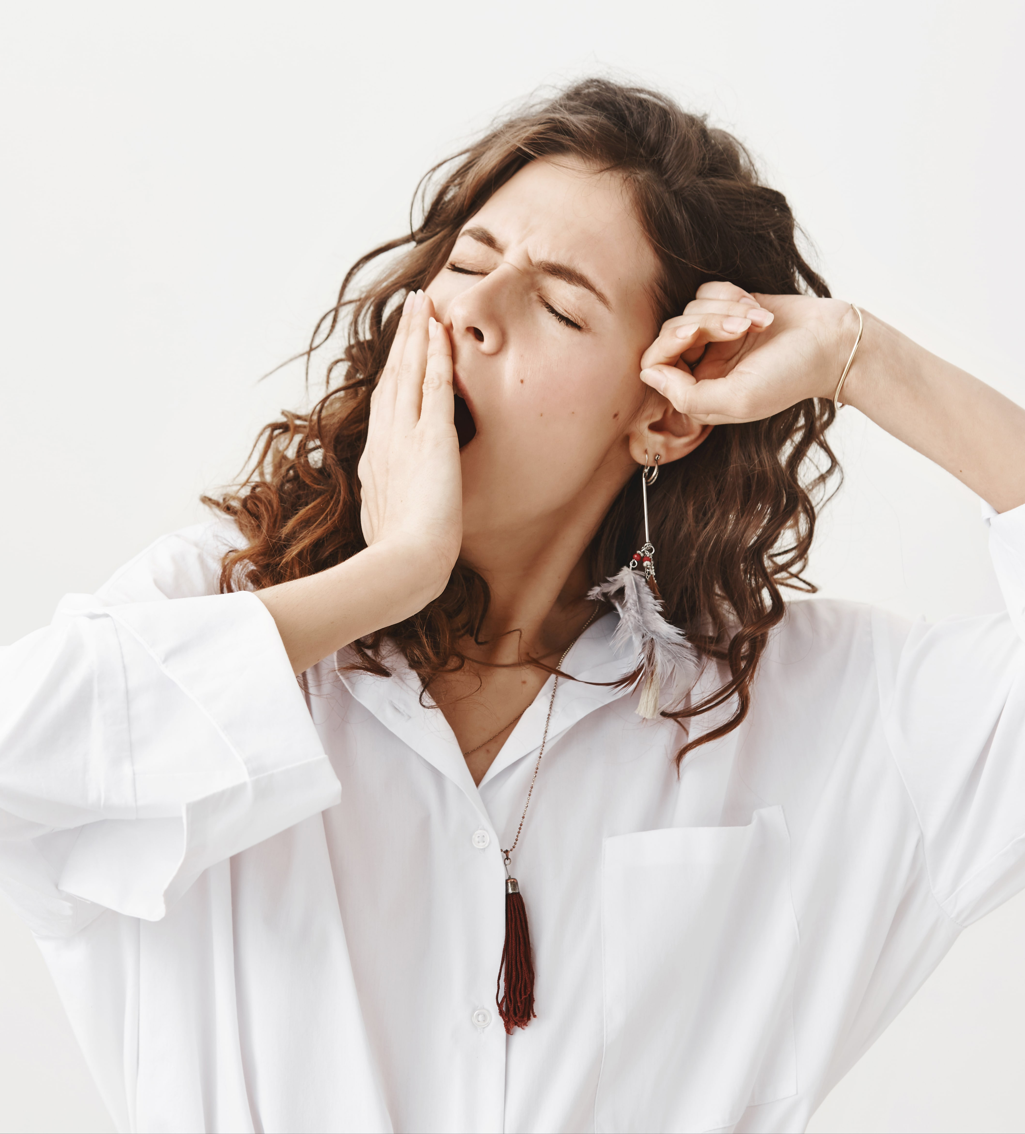 A woman who is a tired bedtime procrastinator yawns