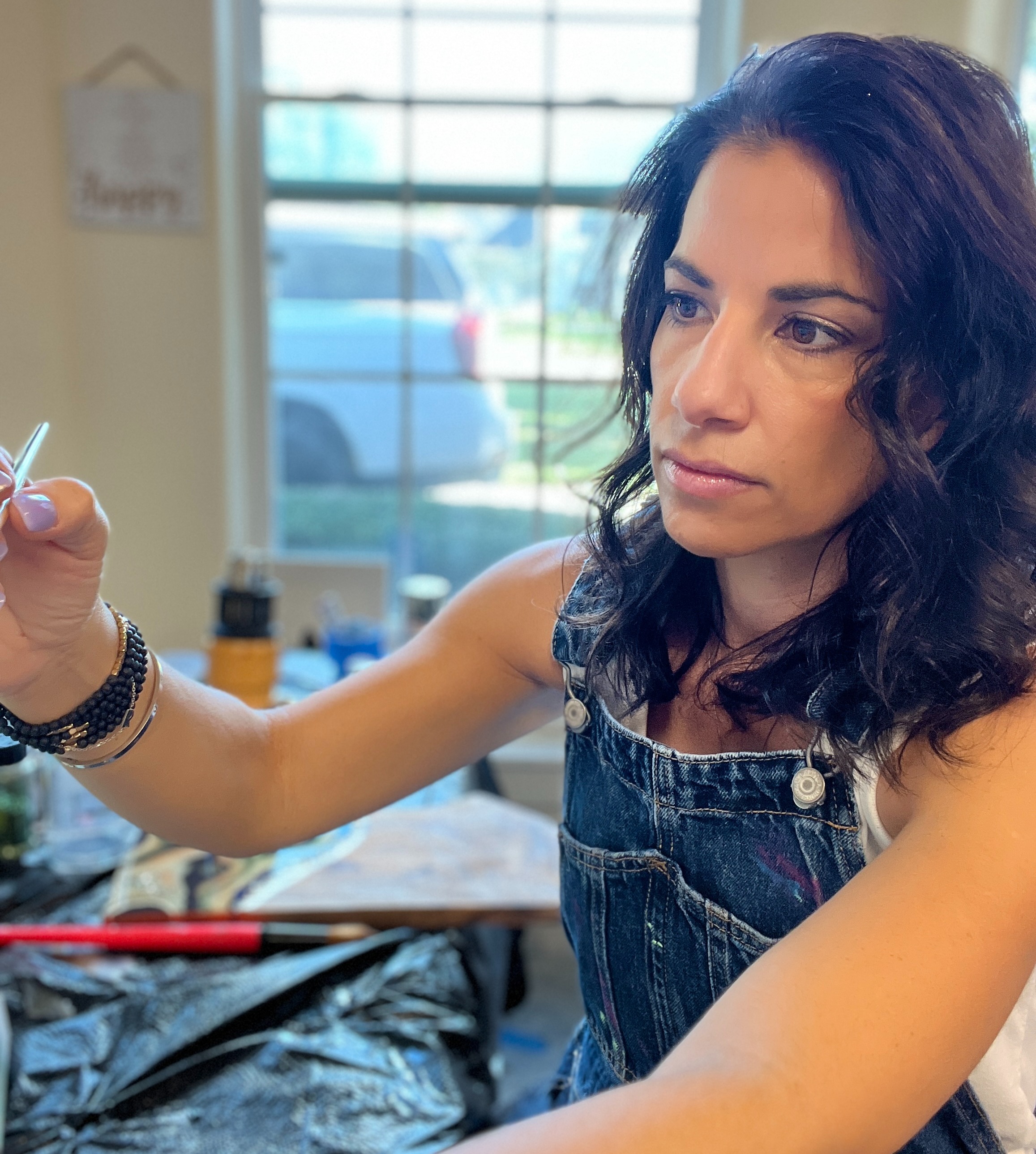 Creative artist holding a vibrant array of paintbrushes, symbolizing the hands-on experience in her online resin art courses.