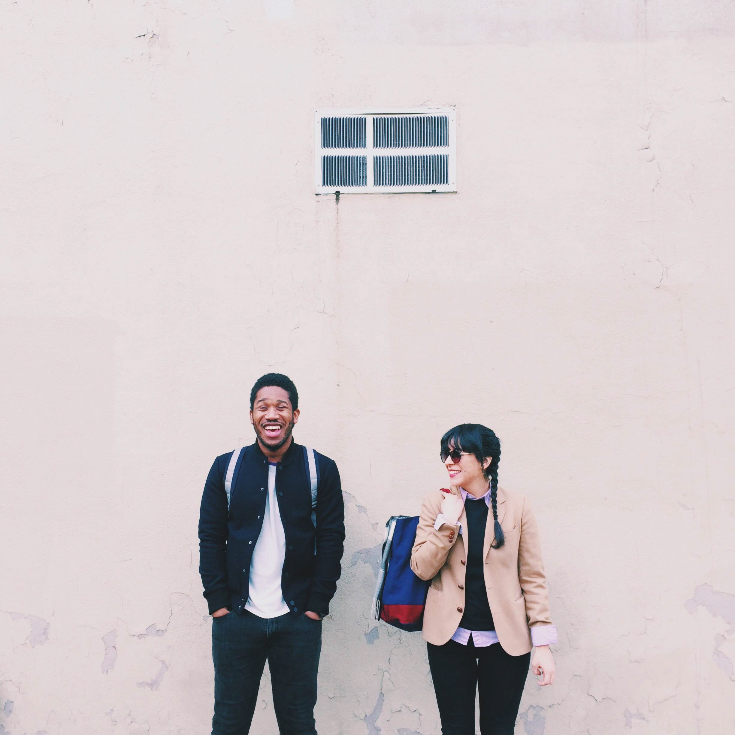 a couple smiling against a wall 