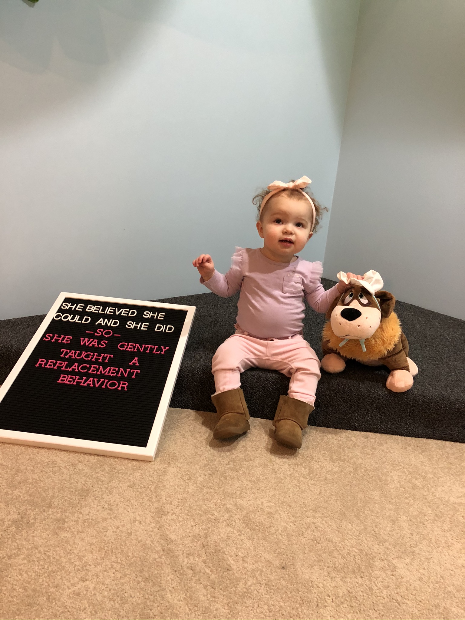 Small child sitting with a sign about replacement behavior