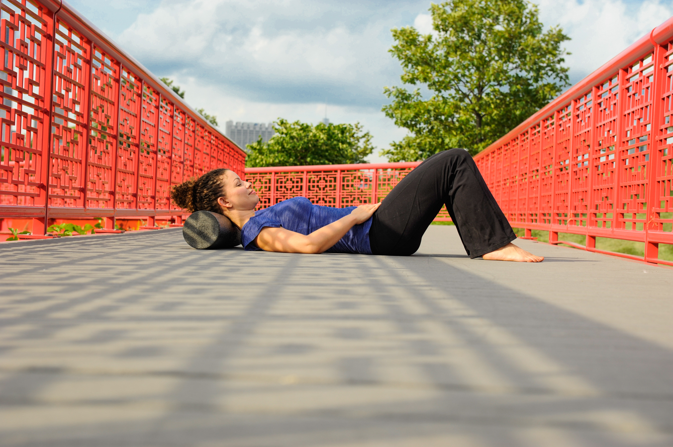 Woman On A Red Bridge Resting Her Neck On A Foam Roller