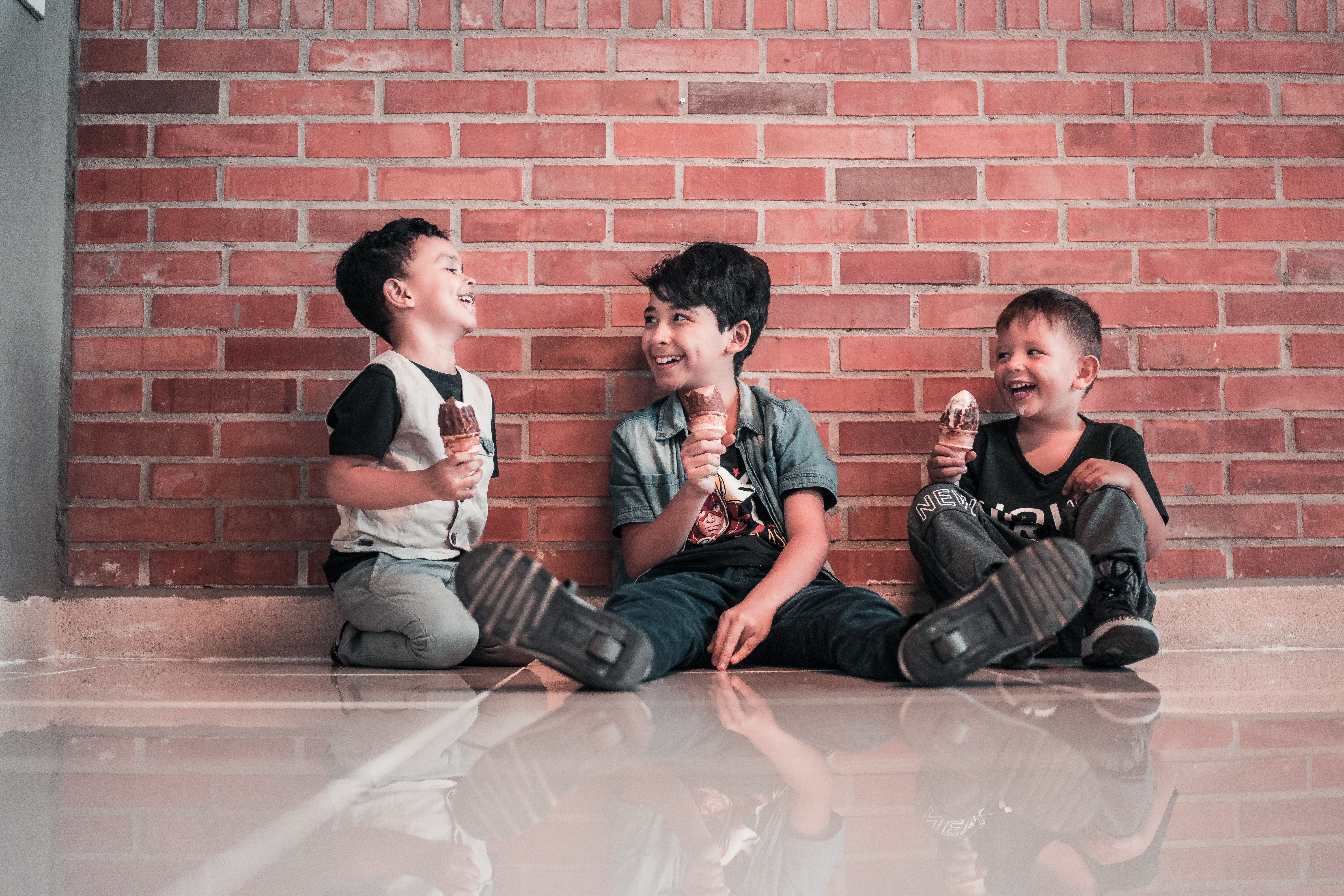 3 kids sitting on the floor laughing eating ice cream