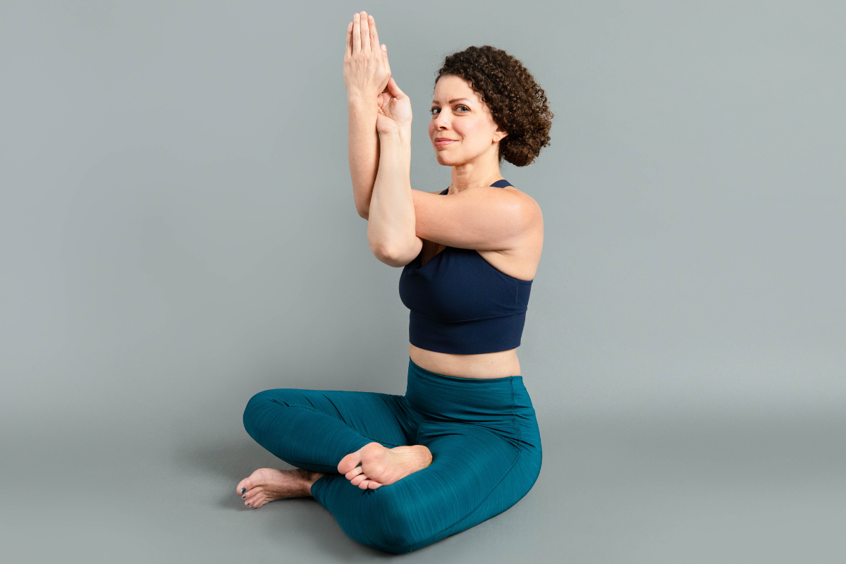 Seated female with arms in eagle pose and legs cross legged position