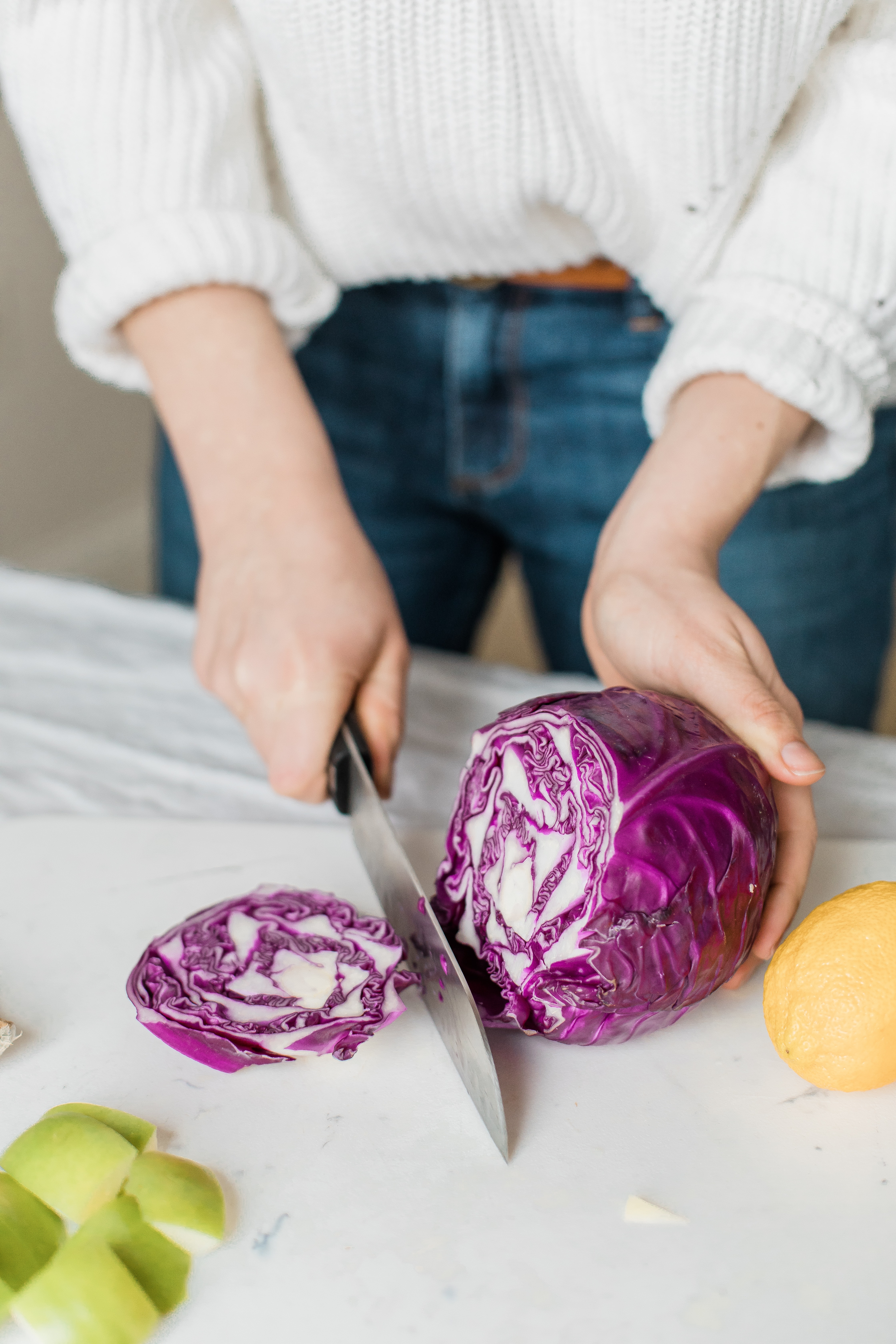 woman&#39;s hands cutting purple cabbage with knife