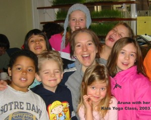 Aruna surrounded by 7 happy children after her yoga class