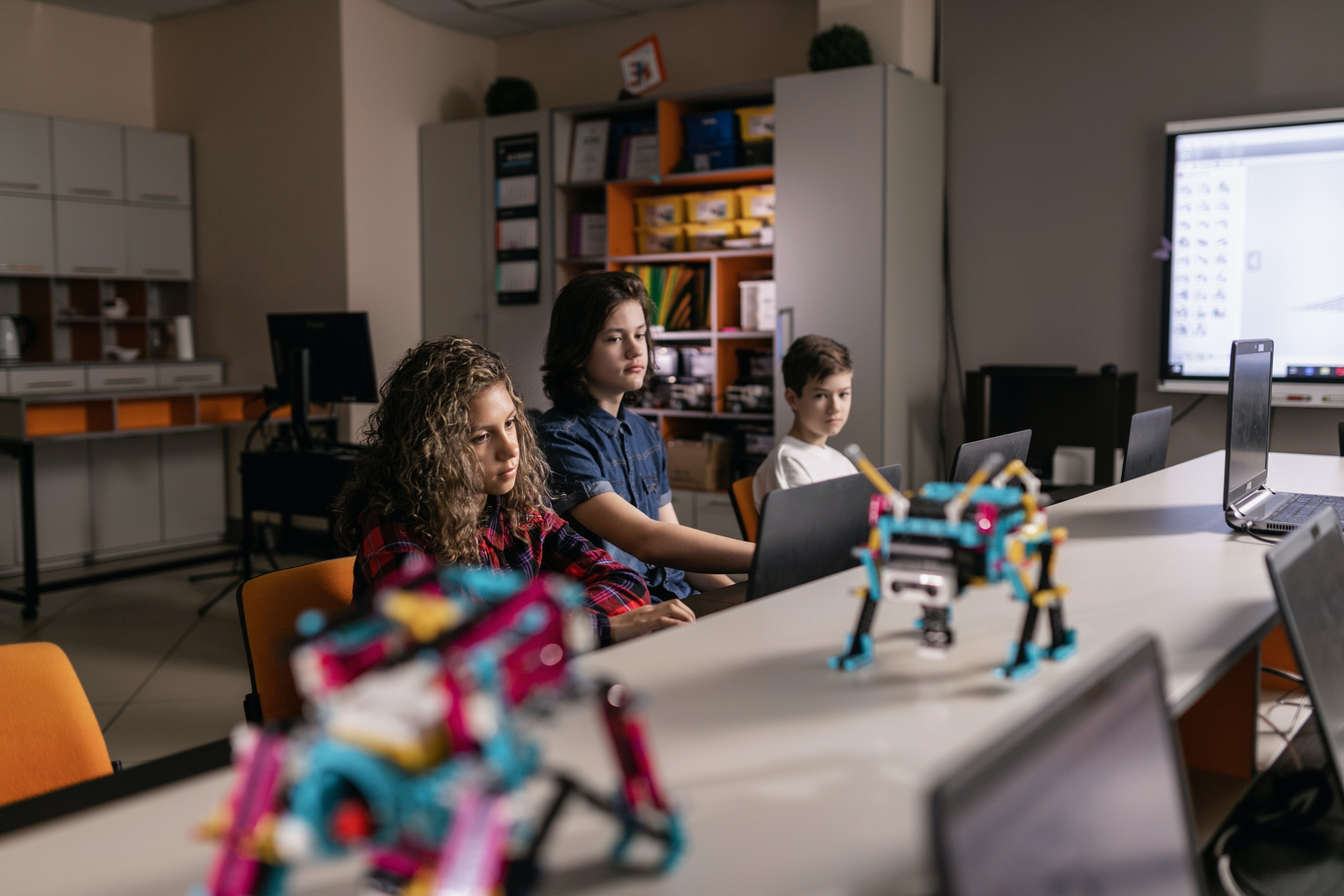 Students sitting at a table looking at small robots