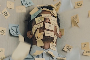 A tired bedtime procrastinator sleeps under post it notes