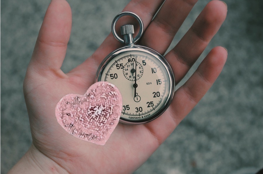 A hand with a stopwatch and heart in the upward facing palm