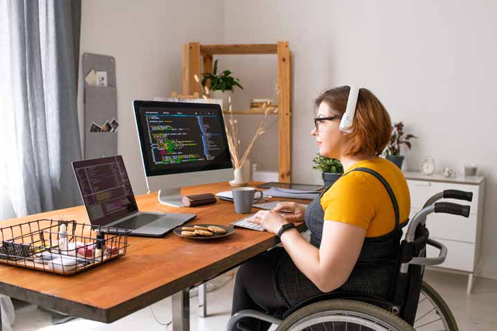 woman at desk in wheelchair working on computer