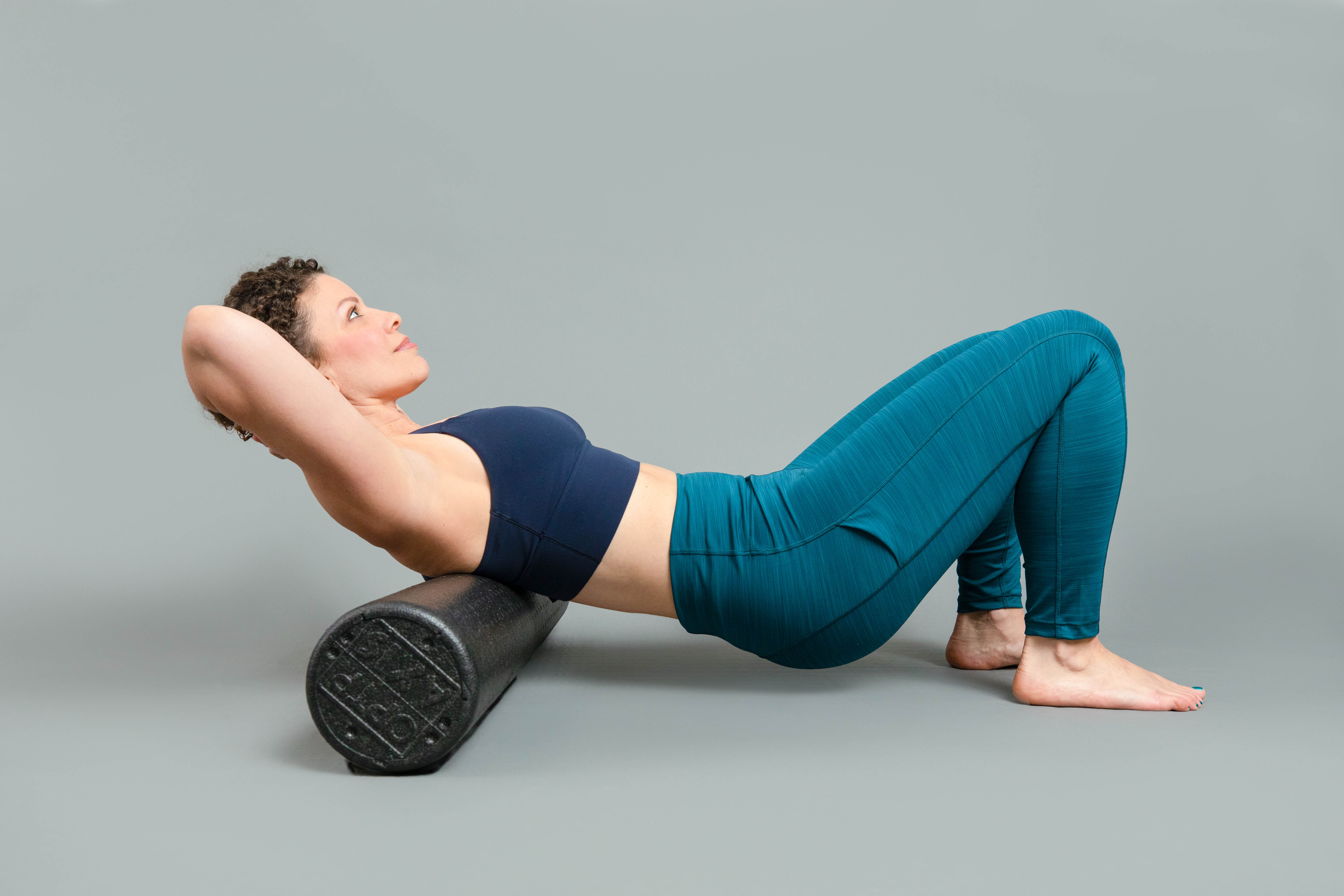 Woman laying back on black foam roller