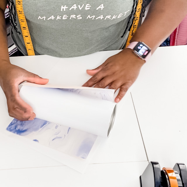 Brown hands crafter is wrapping a white sublimation tumbler with a blue marbled desgn