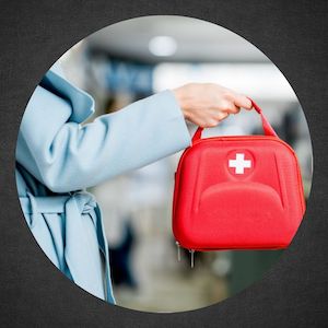 woman in blue coat holding red emergency bag