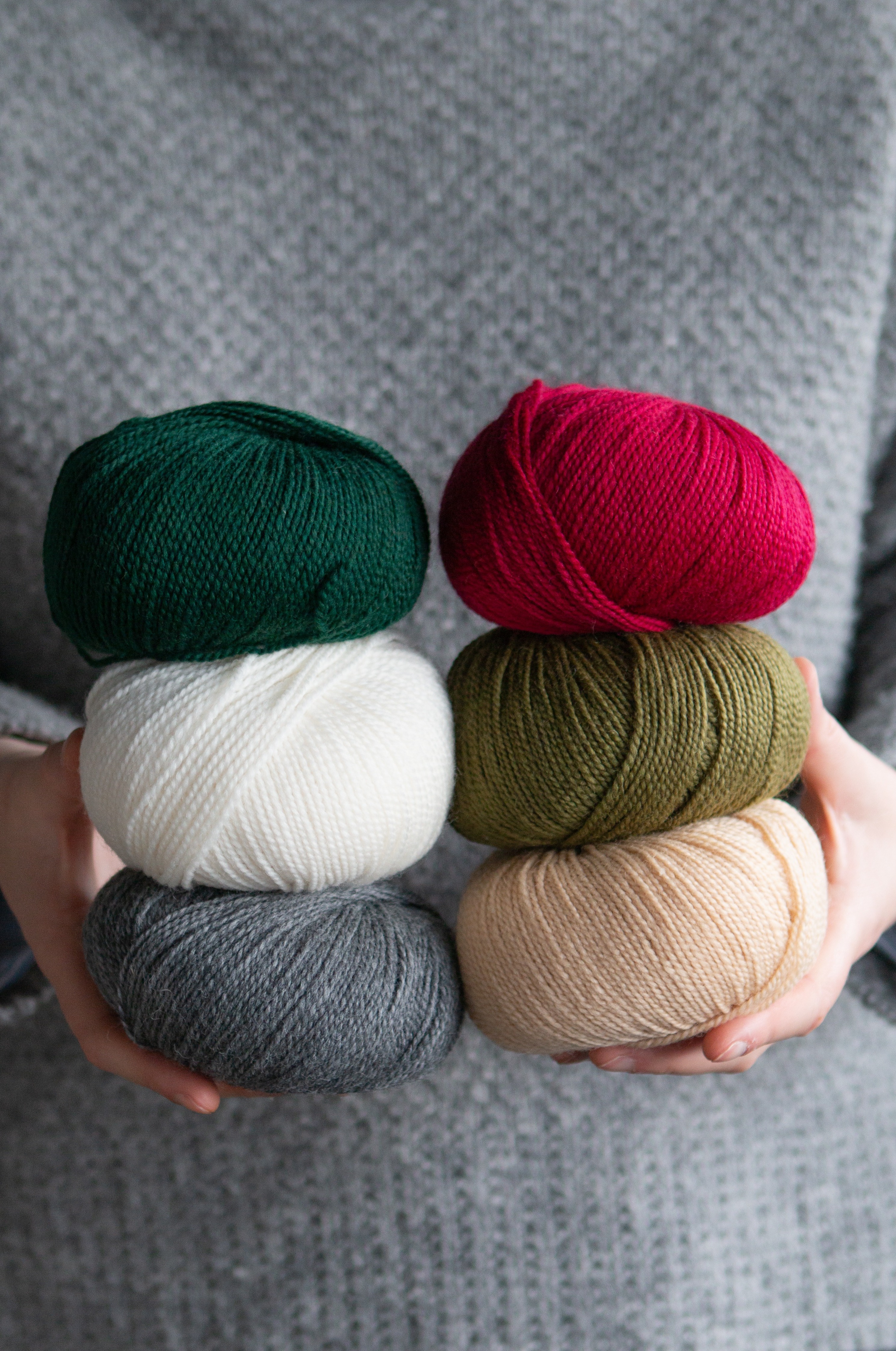 Seasonal yarn option held in hands, six balls of yarn.