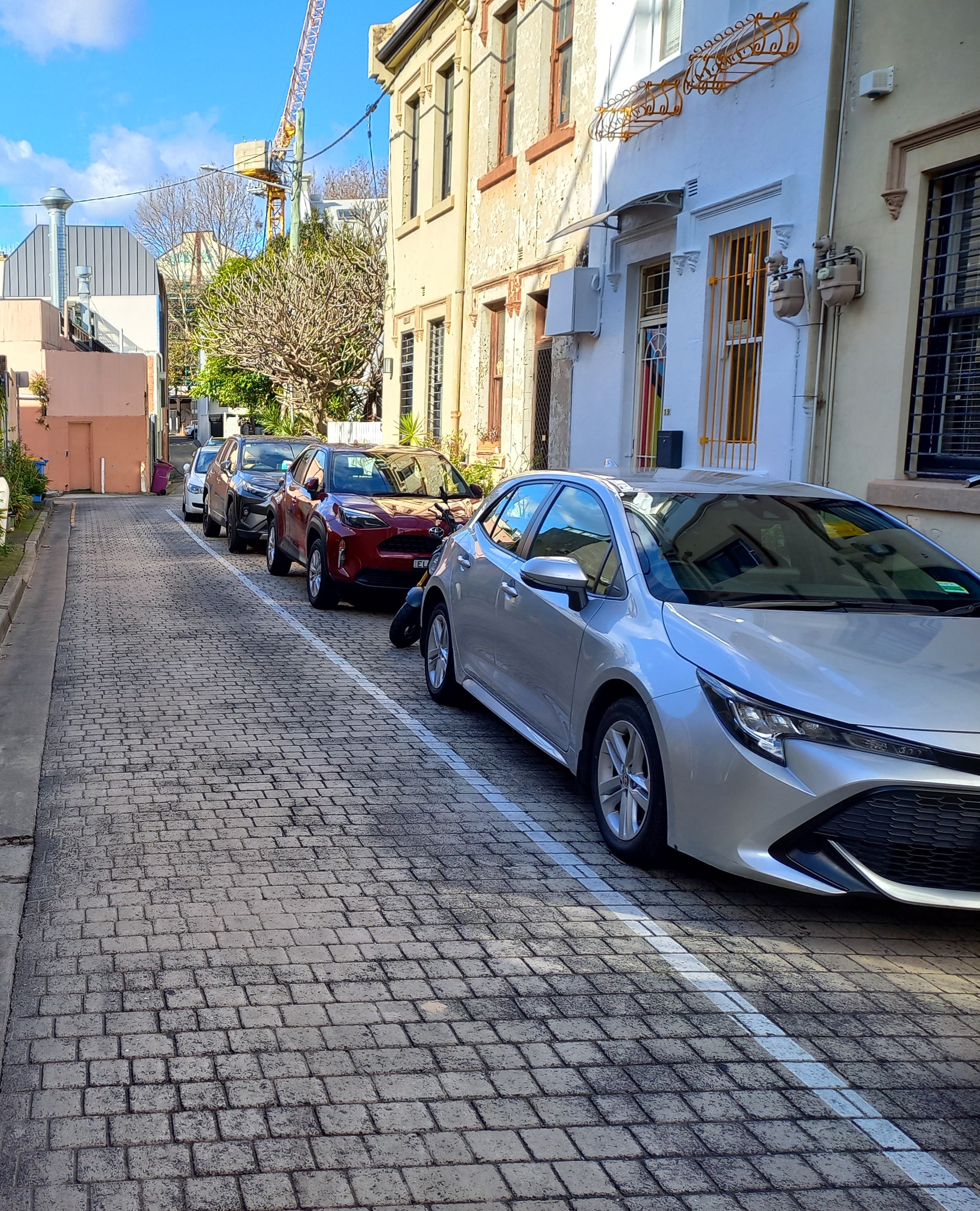 Photo showing street parking in a quiet narrow urban street