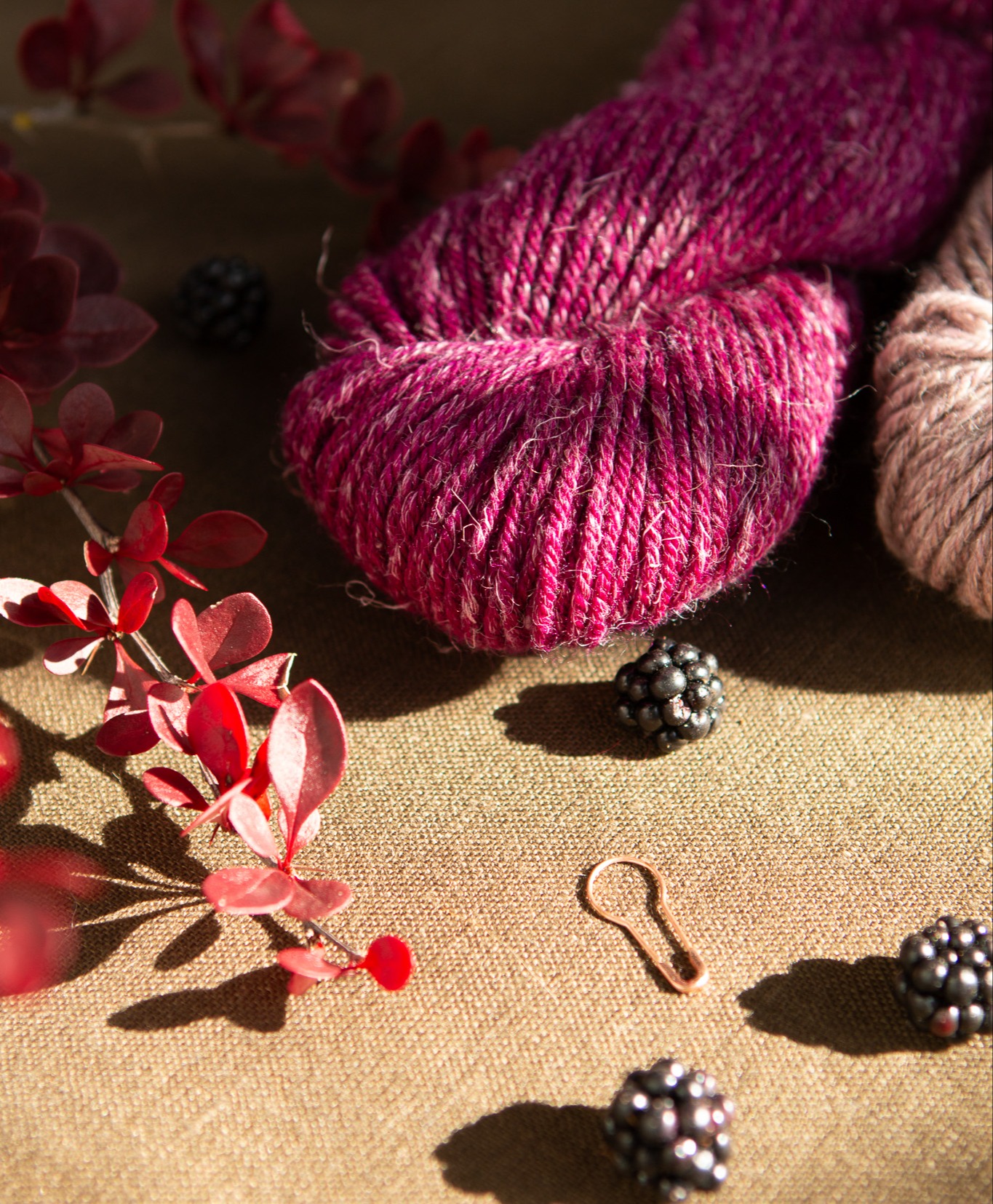 Pink yarn with blackberries and a stitch marker